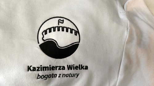 Czarny haft logo Kazimierza Wielka na jasnej koszuli