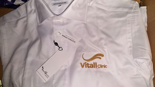 Biała koszula firmowa z haftowanym złotym logo Vitall Clinic