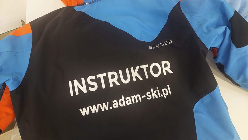 Niebiesko-czarna kurtka narciarska z napisem Instruktor i adresem adam-ski.pl na plecach