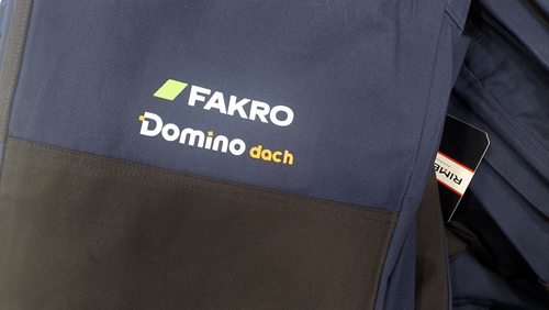 Zbliżenie logo FAKRO i Domino Dach na odzieży roboczej